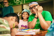 a man and a girl sitting at a table with a group of kids