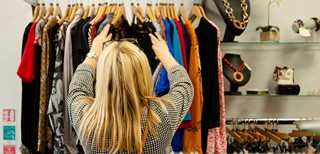 Woman browsing through clothing rail in a Marie Curie store