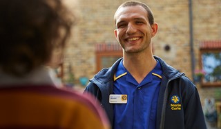 A Marie Curie Nurse is greeted at the front door of a patient's home.