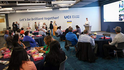 Dr. Richard Van Etten, behind the podium, tells donors and supporters about the research the UCI Anti-Cancer Challenge has funded at a kickoff ceremony on May 30, 2024.