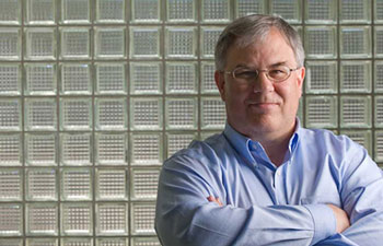 michael demetriou neurologist uci health multiple sclerosis standing in front of glass blocks wearing a light blue shirt