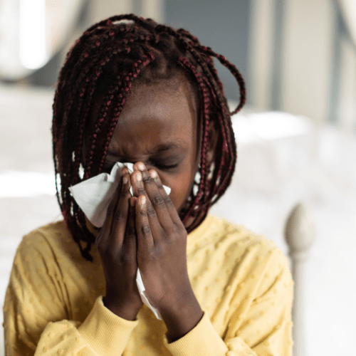 girl sneezing into tissue