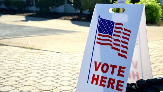 Sign on a sidewalk that says Vote Here