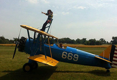 woman wing walking on top of biplane