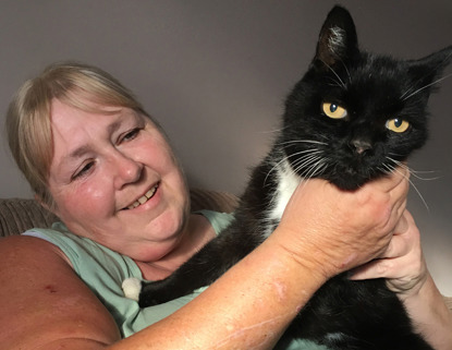 blonde woman holding black and white cat