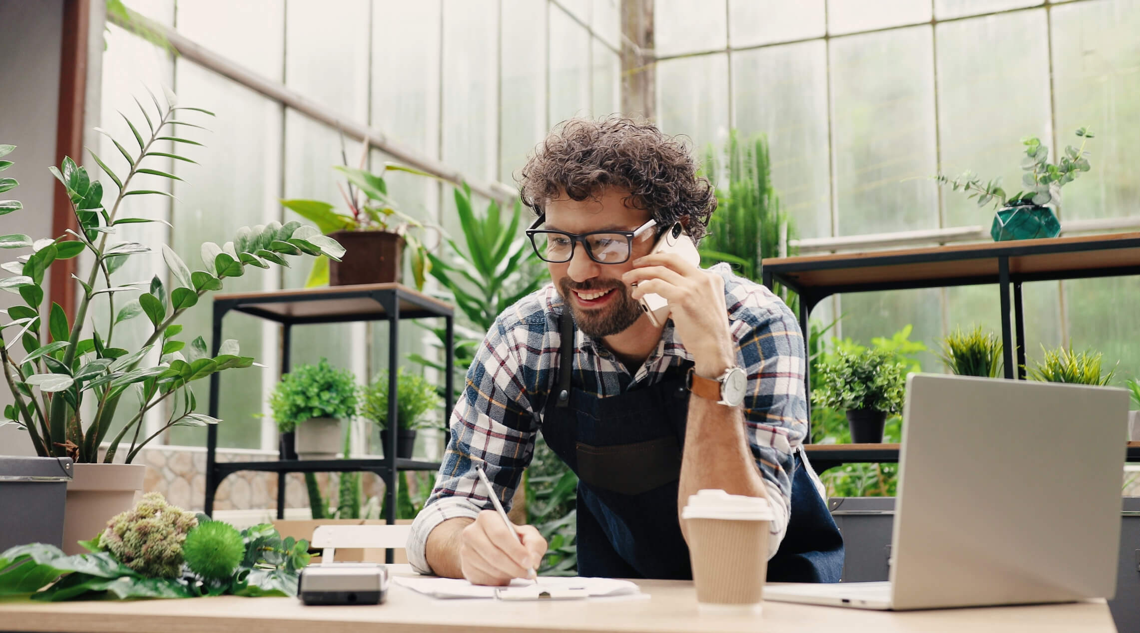 Image of a small business owner on the phone leaning on a bench.