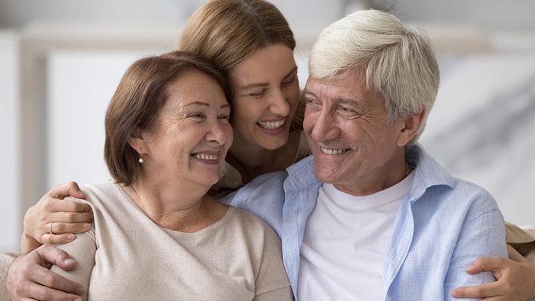 three adults smile and embrace each other