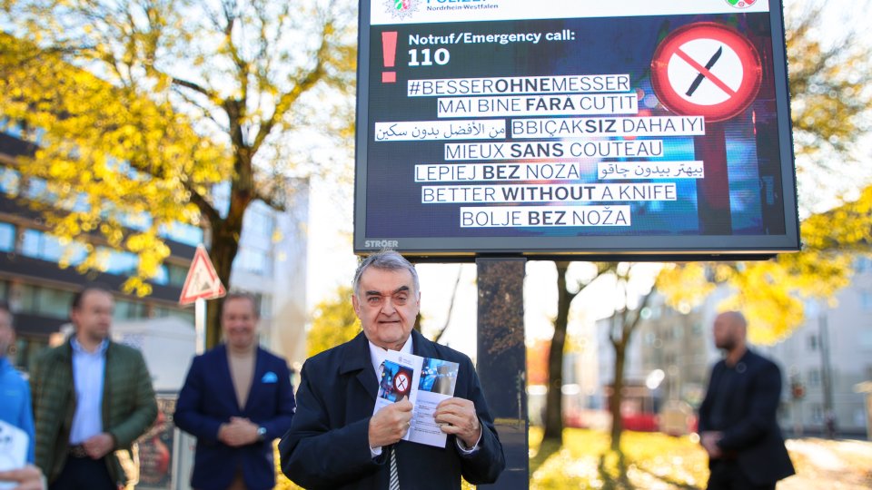 NRW-Innenminister Herbert Reul steht vor einer digitalen Stadtinformationsanlage mit der Kampagne #besserohneMesser.