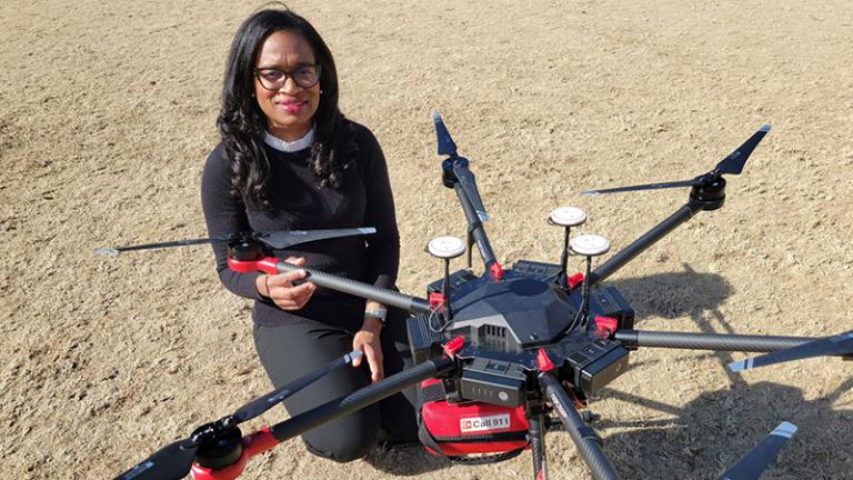 Photo of researcher Monique Starks, M.D., kneeling next to medical drone equipped with an AED device. Source: Forsyth County Sheriff's Office