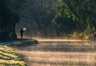 Person running alongside canal with evaporation steam