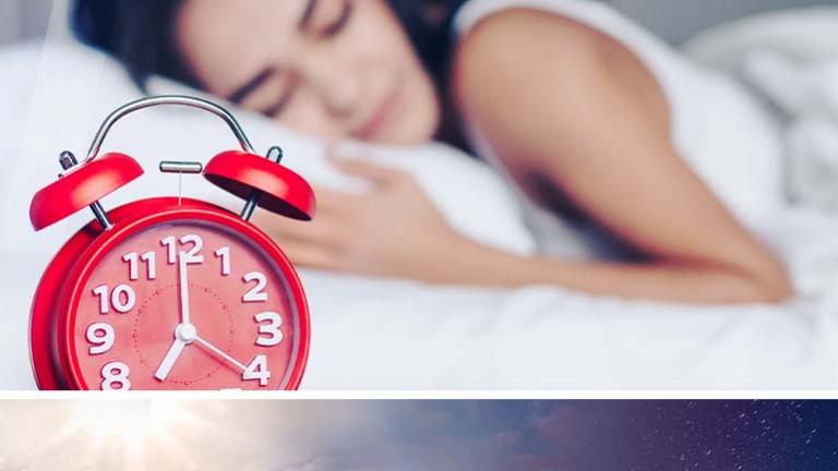 red alarm clock with woman sleeping in the backgroun