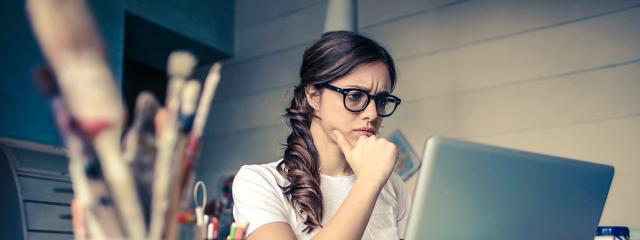 Woman in an art studio looking at computer with an expression of concern