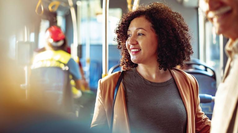 A woman is standing inside a shuttle, smiling and looking to the side.