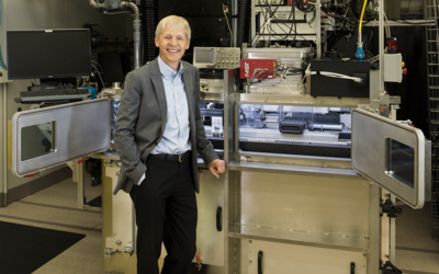 NIST Chief Metrologist Jim Olthoff stands in front of equipment in a lab. 