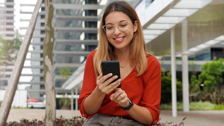 young woman smiling while looking at phone