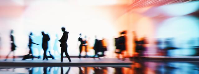 Silhouttes of people walking in front of a multicoloured background