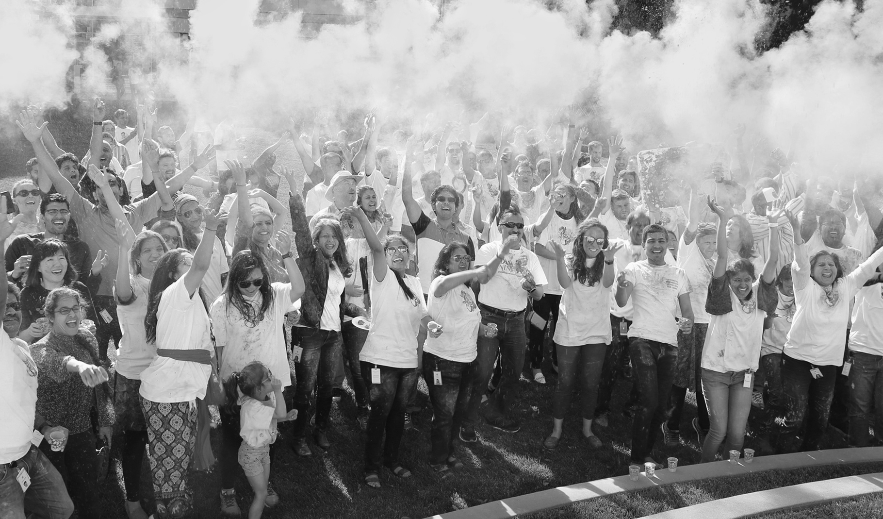 Photo of a large group of employees cheering outdoors at an Apple campus.