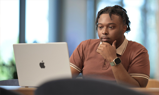 Quincy, seated, looking at his MacBook screen