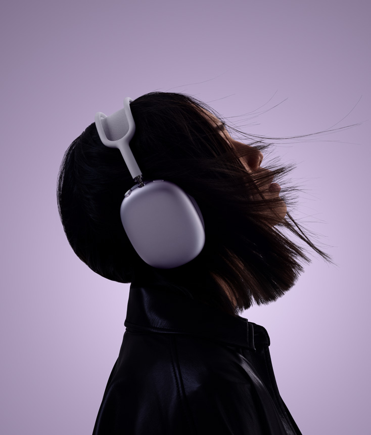 A woman’s head, shot from the side. She’s looking slightly up and wearing AirPods Max.