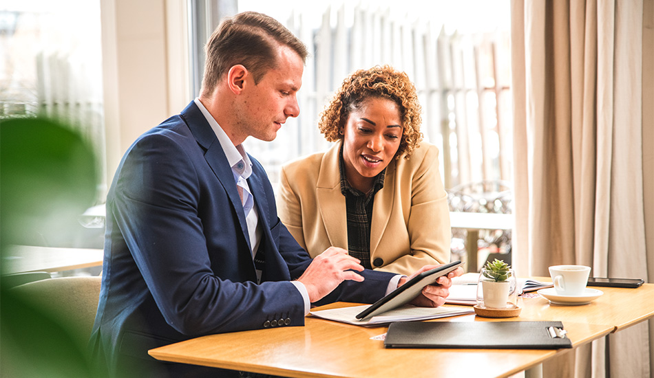 Two people collaborating on a tablet, symbolizing the innovation and teamwork behind Equifax's 100+ new product introductions for four consecutive years.