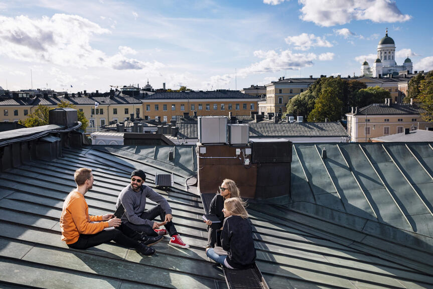 Neljä ihmistä istuu katolla Katajanokan alueella