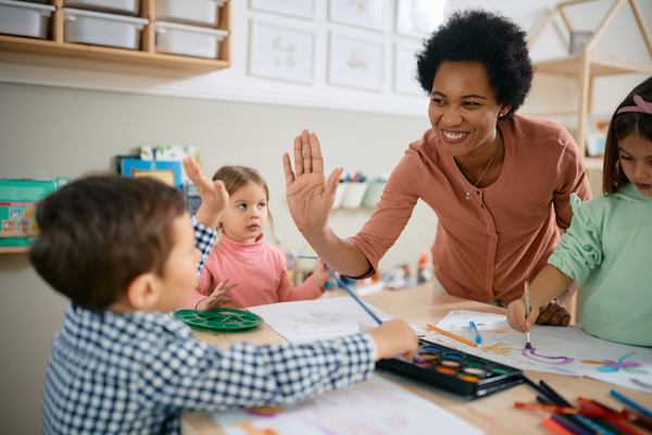 An educator high-fives a young student in a...