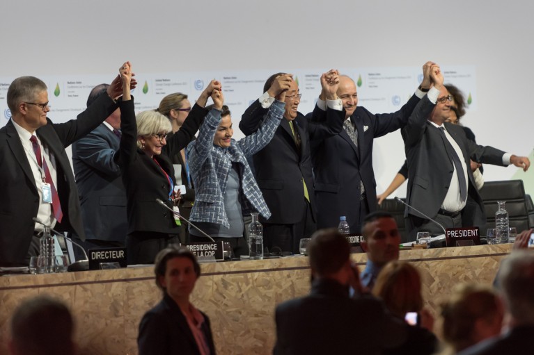 A row of people stand and raise holding hands at the COP21 Climate Conference in Paris