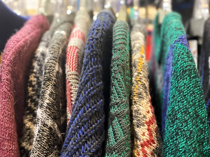 Close-up of a clothing rack of multi-coloured vintage sweaters at a flea market