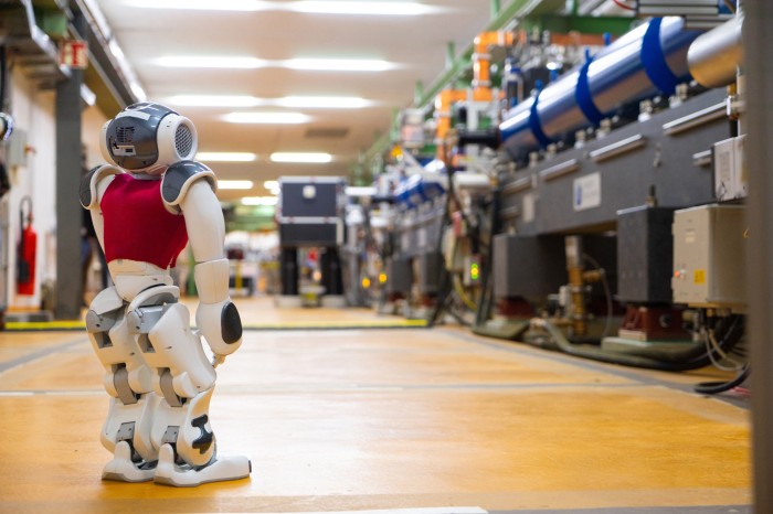 A low-angle rear view of a Nao humanoid robot in the tunnel of the ARES particle accelerator facility at DESY