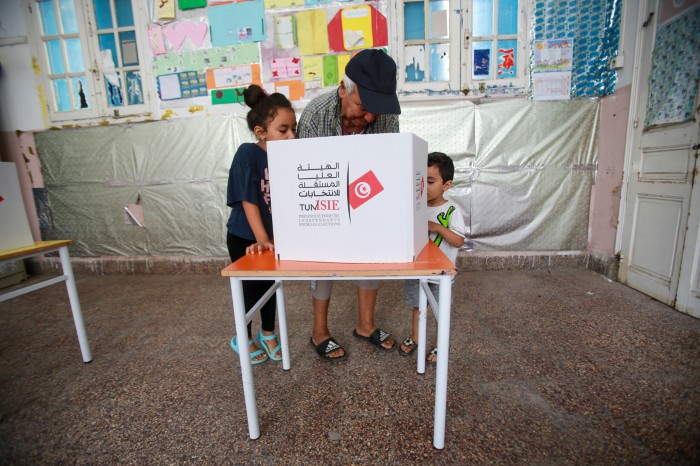 A Tunisian man with two young children casts his vote at a polling station