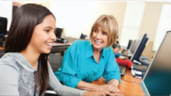 Student and teacher sitting in front of computer monitor.