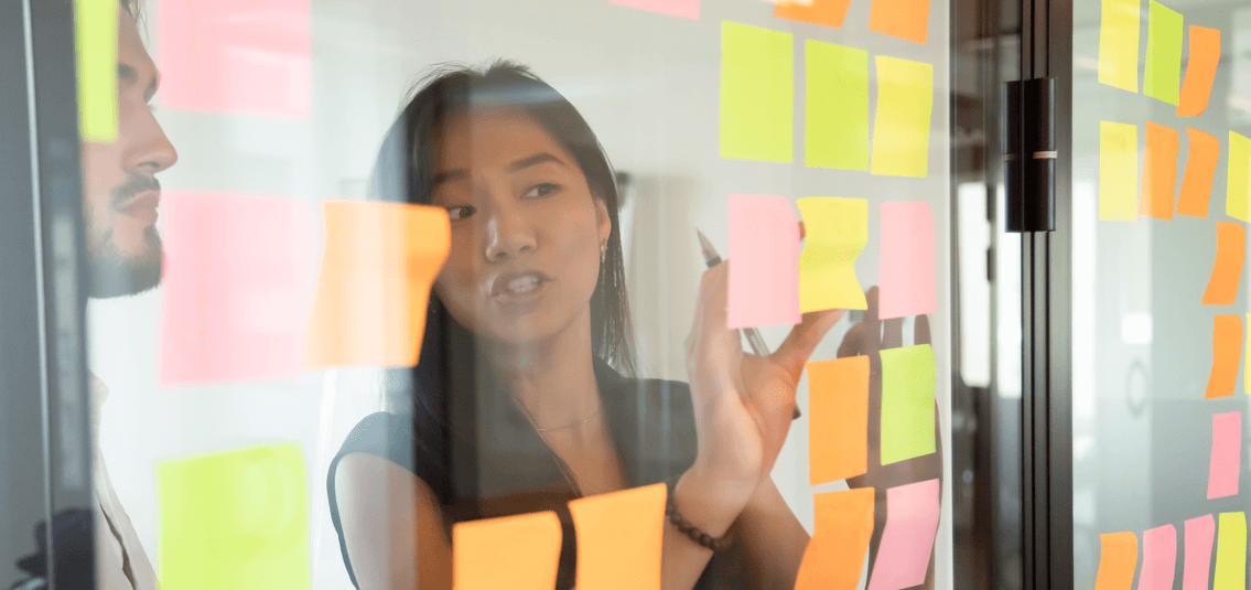 Young lady adding notes on a glass partition