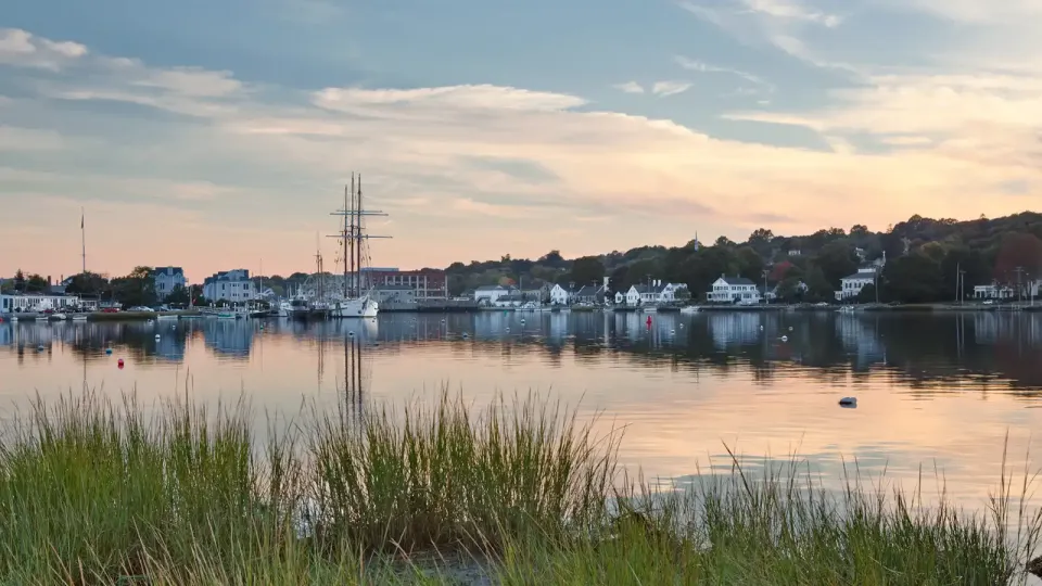 Connecticut port town inlet with white clapboard houses and boats at dusk