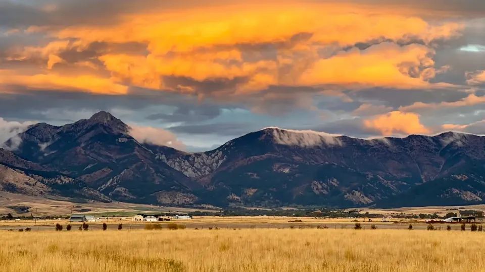 Foothills of Montana mountains with tall brown grasses and cloudy skies at sunset