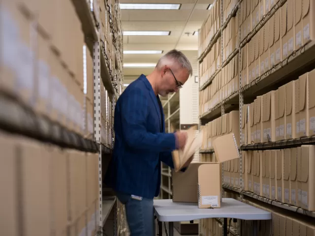 Person standing in an aisle between shelves.