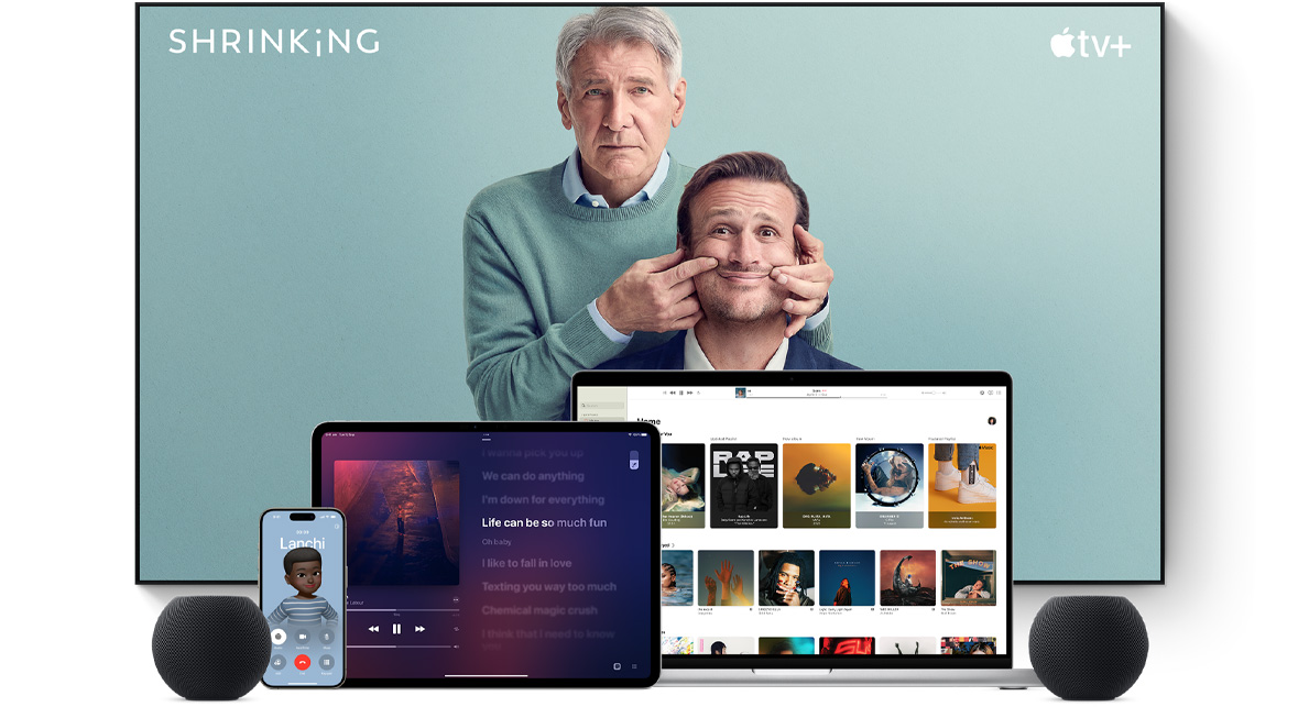 Large flat screen television showing two male characters from the Apple TV+ series shrinking. A MacBook Pro, an iPad, an iPhone and a Midnight HomePod mini are arranged in front.
