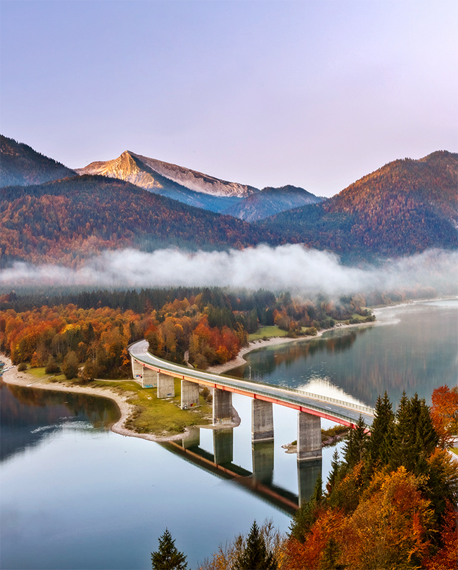 Un pont enjambant un lac avec des montagnes en arrière-plan.