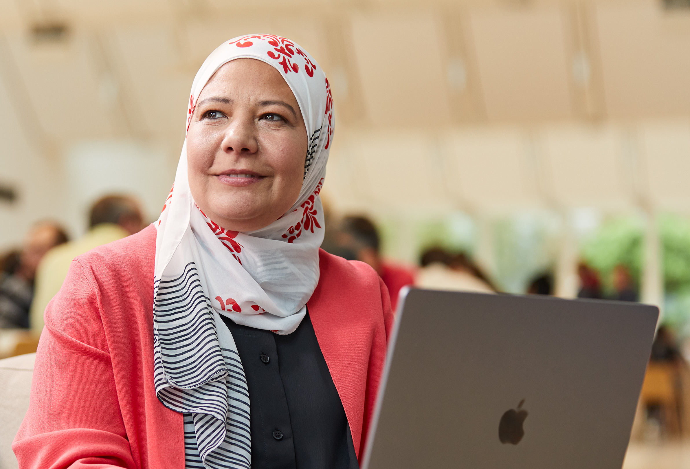 Une employée Apple travaille sur un MacBook. Elle est assise, et son regard est tourné vers la gauche.