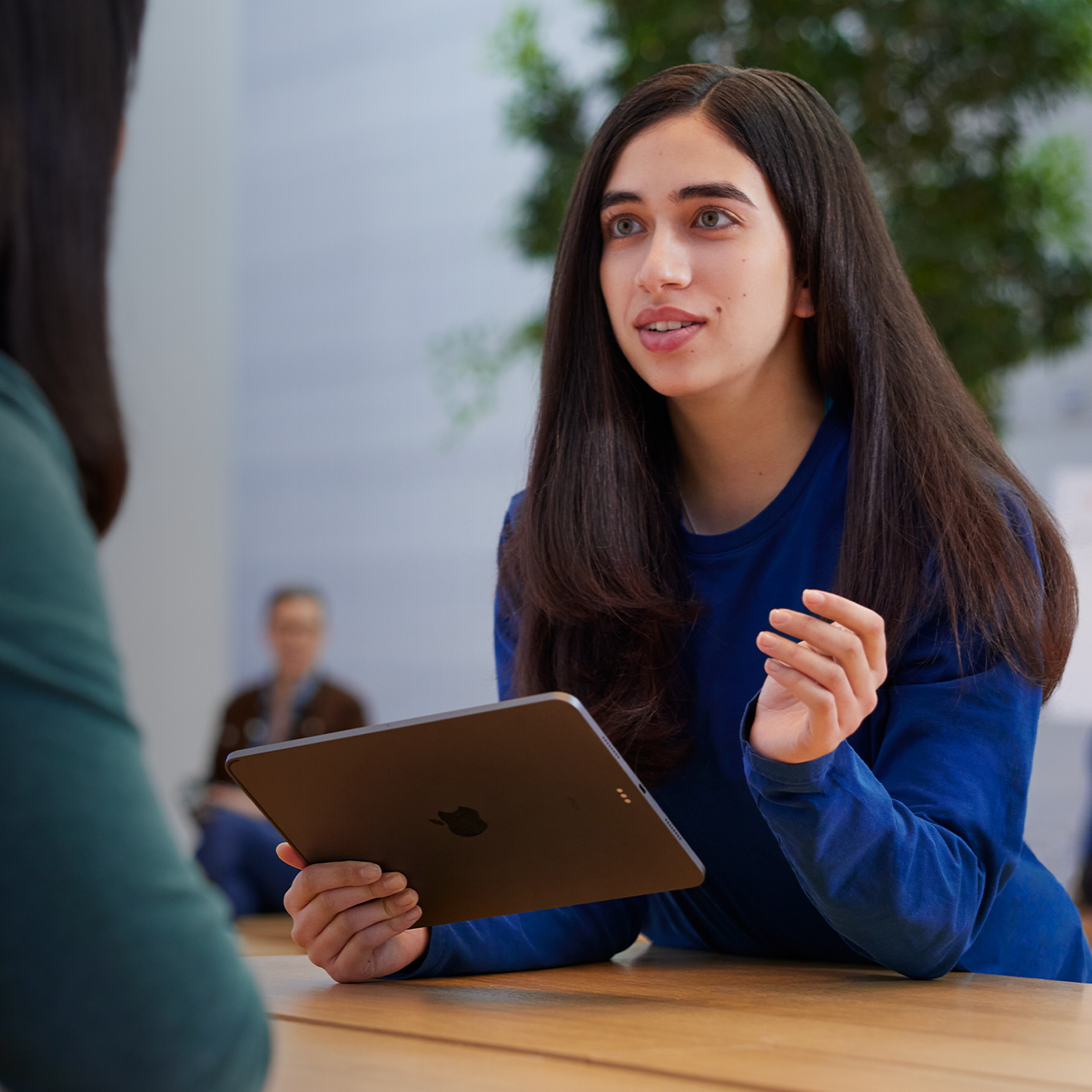 A Serene segura um iPad e conversa com uma cliente.