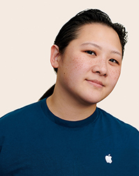 Persona del equipo de Apple Retail con el pelo largo sonriendo a la cámara.