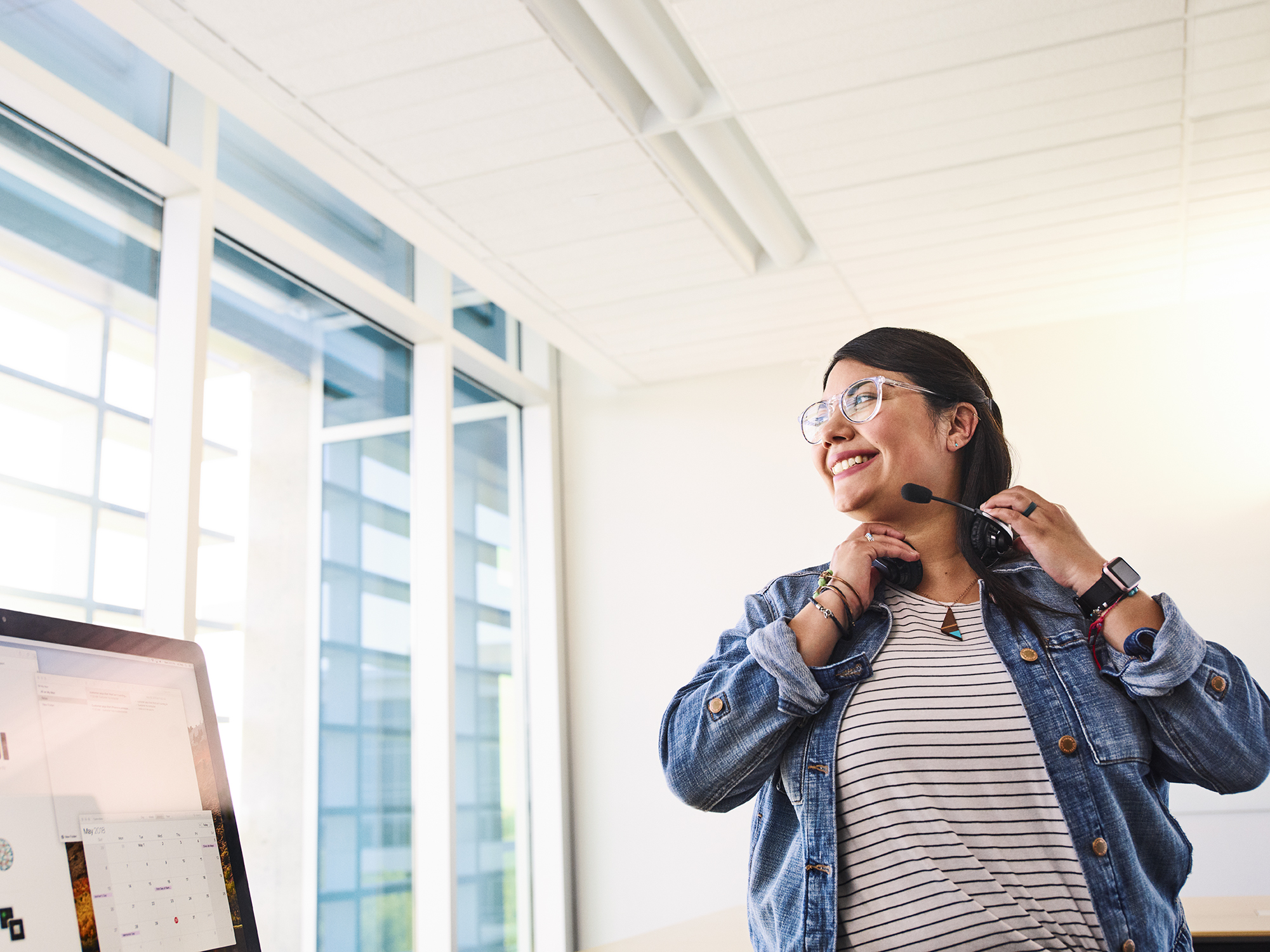 Funcionária da Apple com um headset sentada em frente a um computador.