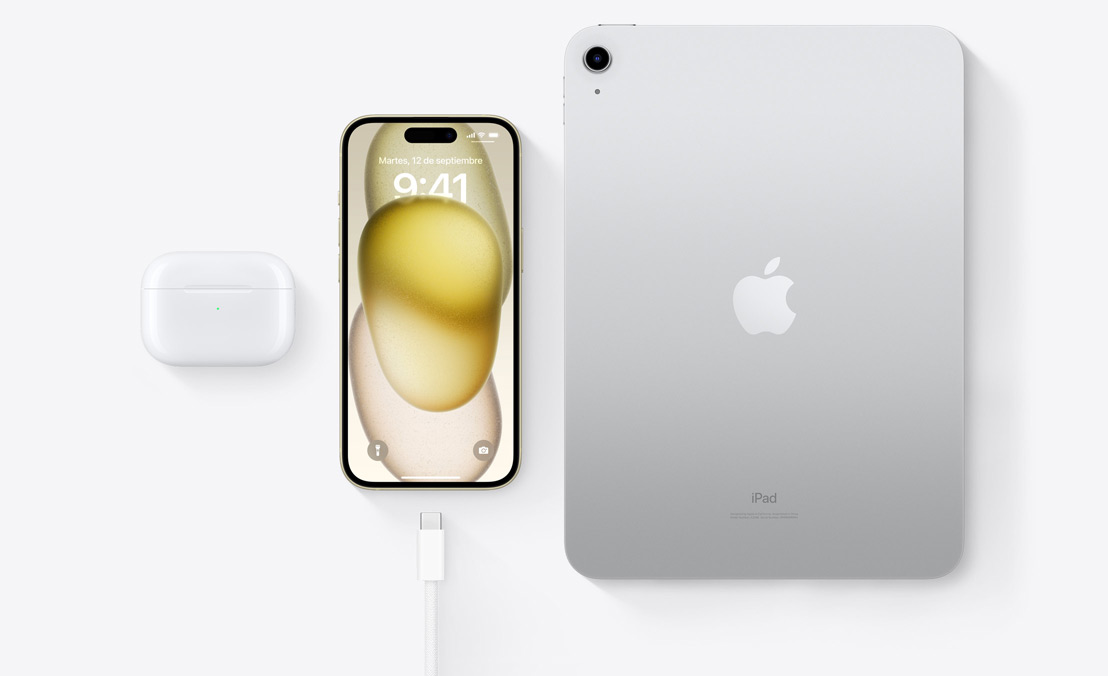 A birds-eye view of AirPods Pro, iPhone 15, and an iPad with a USB-C connector to demonstrate how all three devices can be charged using the same USB-C cable.