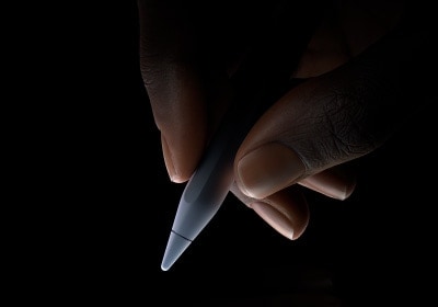 Une main tient le tiers inférieur de l’Apple Pencil Pro entre le pouce et l’index, en position d’écriture.