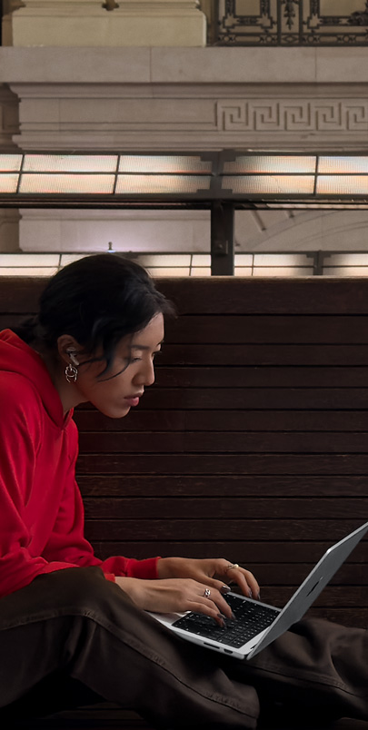 Una persona que está al aire libre, de noche, tiene una MacBook Pro apoyada en su regazo conectada a un dispositivo con un trípode que apunta hacia las estrellas.