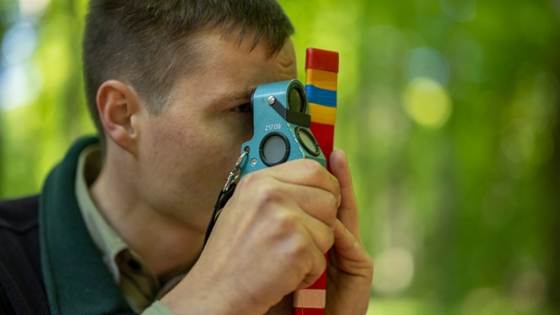 Person im Wald schaut durch ein Messgerät