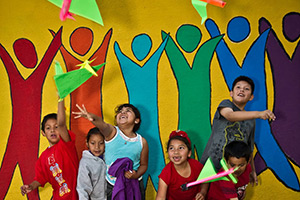 A group of children in front of a colorful wall.