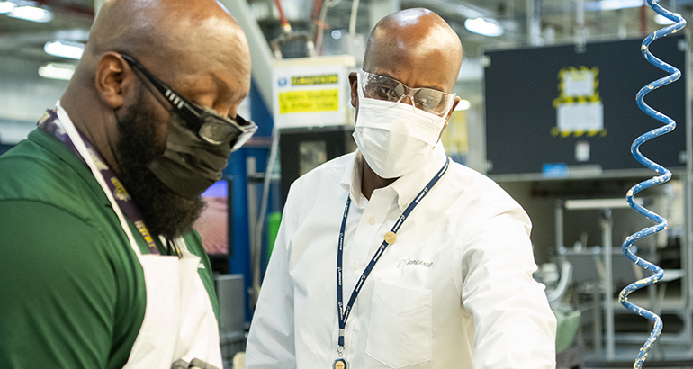 two men in masks working in factory