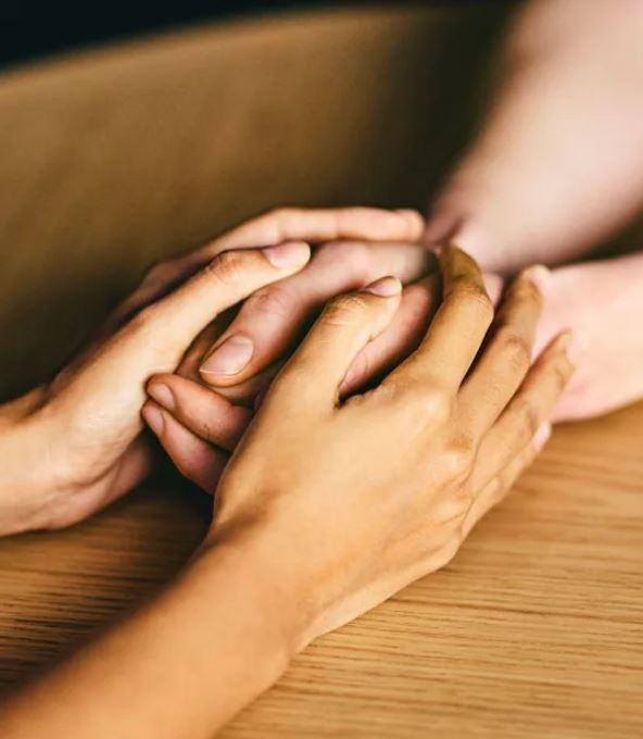 Set of hands holding another set of hands in supportive manner