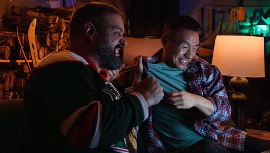 Two men streaming a hockey game in their garage.