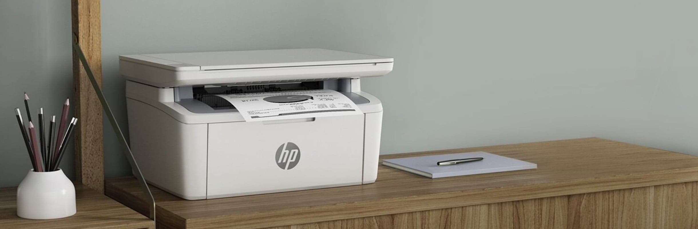 The HP printer is on the dresser, next to it there is a notebook and on the other side there are pencils in a container